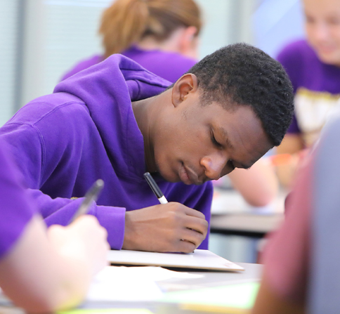 Focused student sitting at a table in class and taking notes